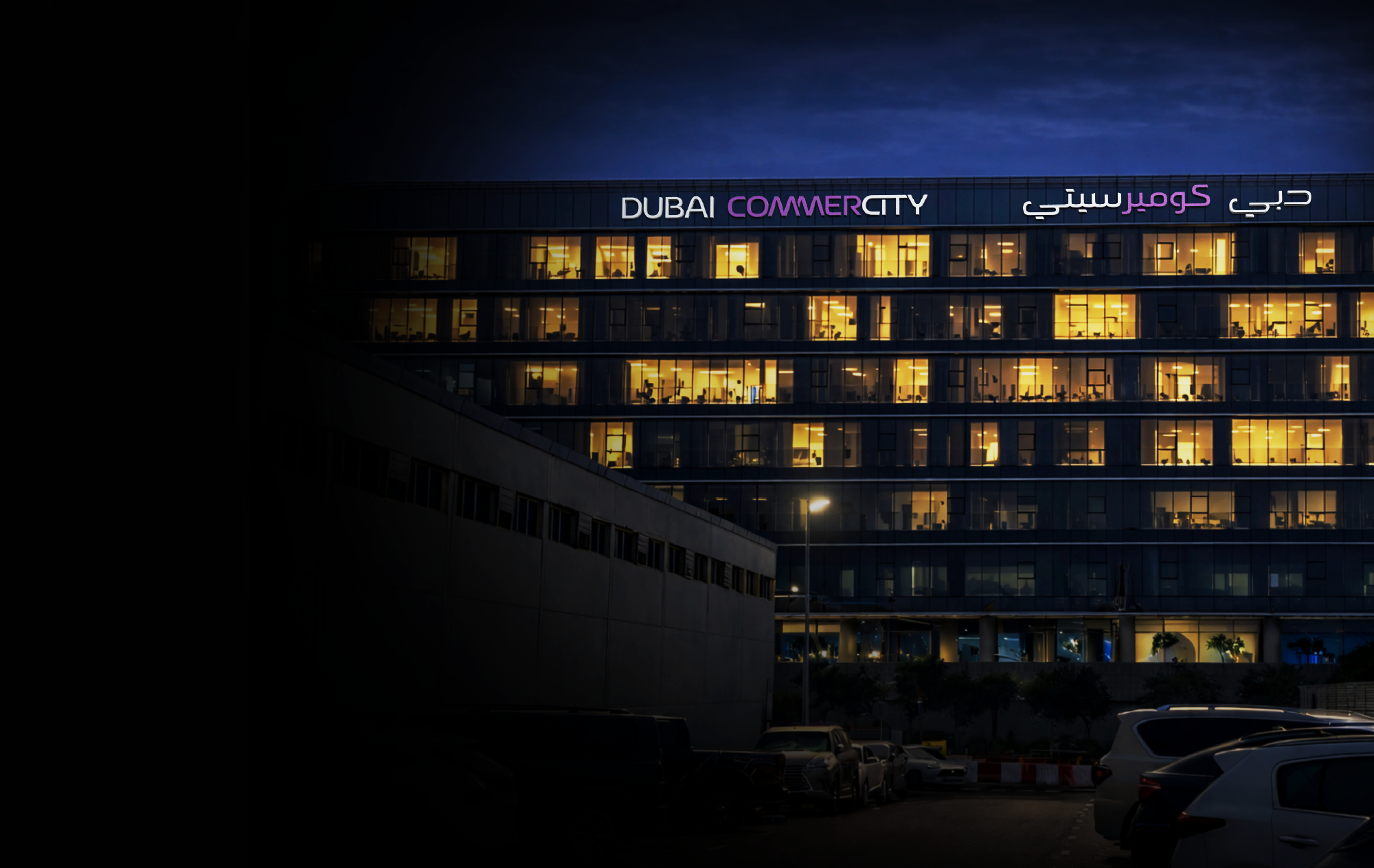 Dubai CommerCity office building at night with illuminated project signage